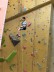 Kind hängt weit oben an der Kletterwand runter
