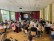 Viele Menschen sitzen in der Aula und schauen auf eine Leinwand mit Fotos (Diashow) 