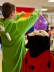 Verkleidete Kinder als Drache und Marienkäfer feiern mit Luftballons in bunter Umgebung.