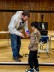 Schüler und Schulsozialarbeiter stehen auf einer Bühne und dem Jungen wird ein Preis übergeben 