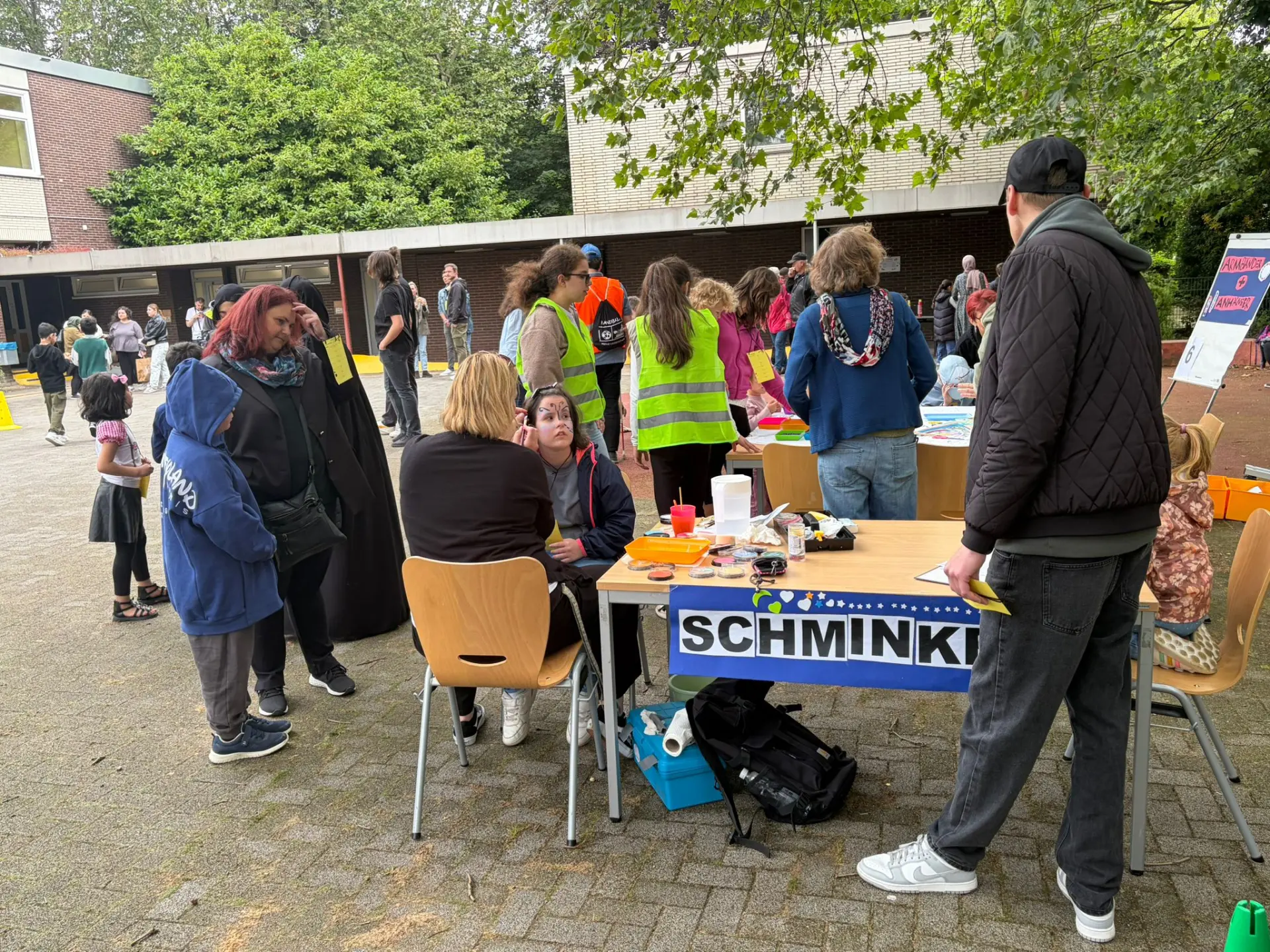 Schülerin wird von einer erwachsenen Person am Kinderschminkstand im Gesicht geschminkt 