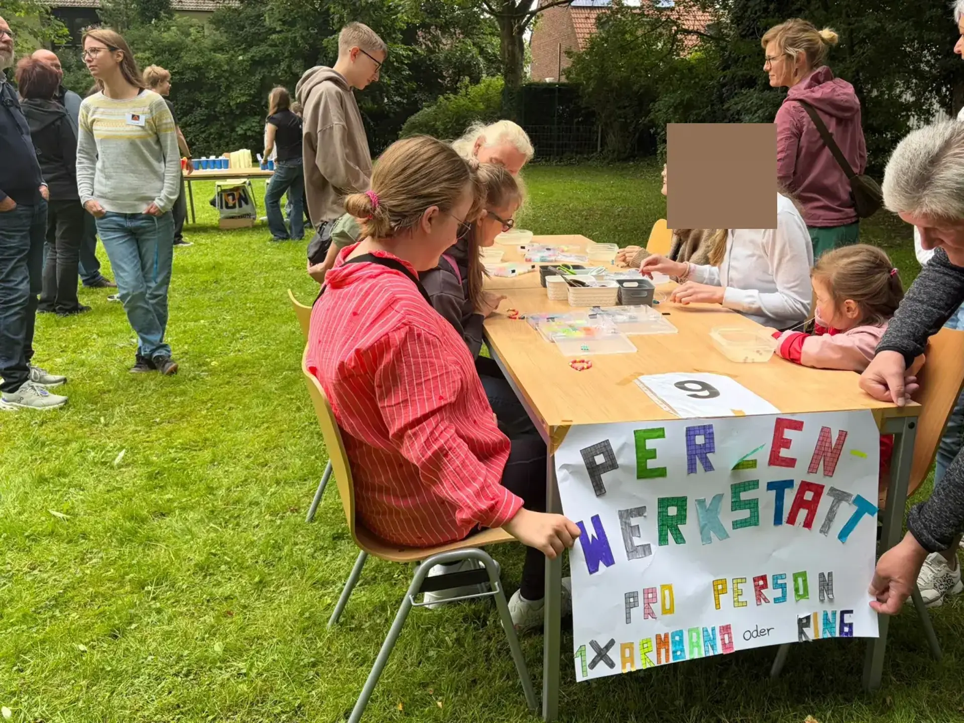 Mehrere Schüler:innen sitzen an einem Tisch und gestalten Schmuck aus Perlen 