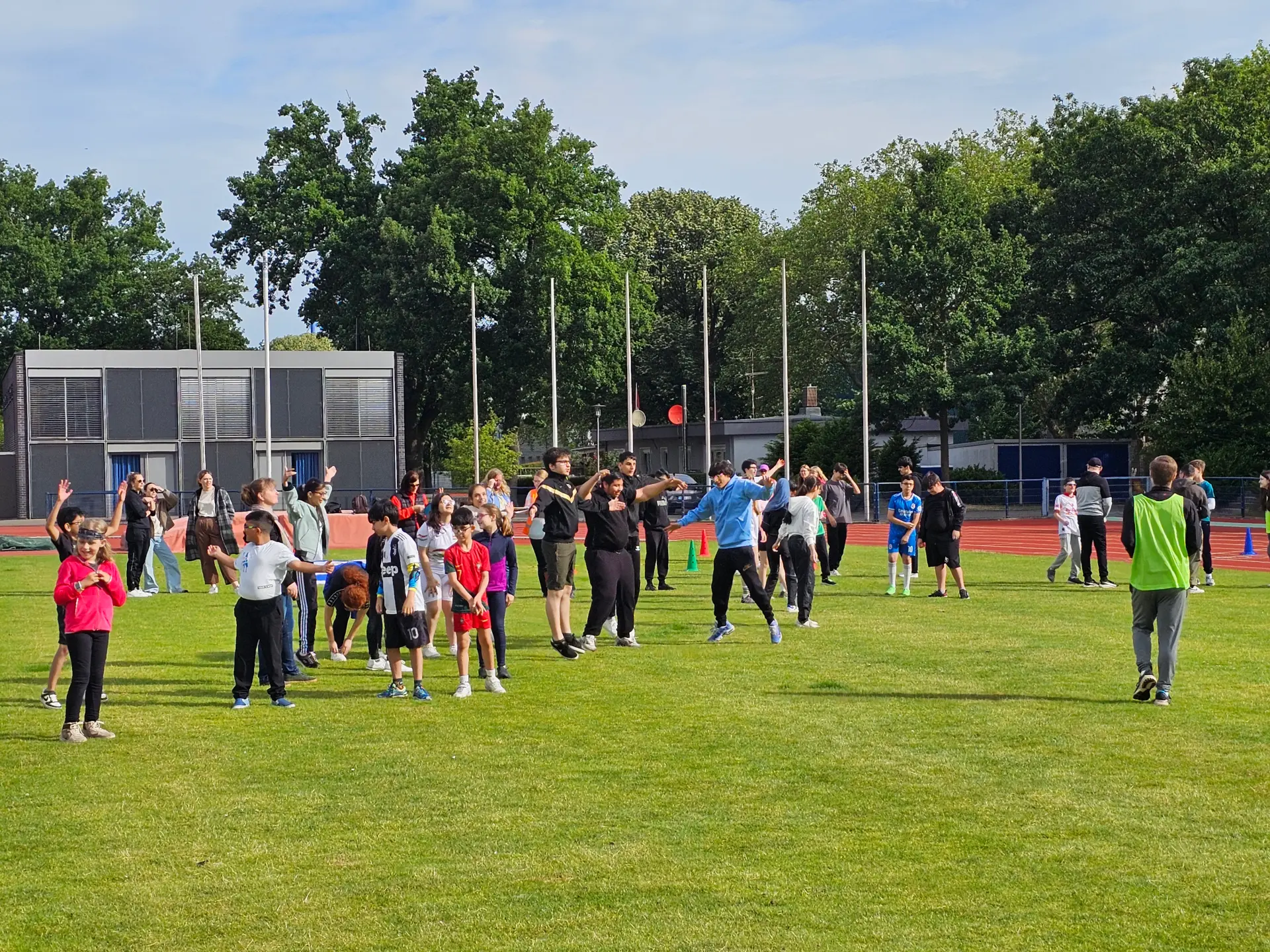 Schülerinnen und Schüler, die sich auf einer großen Wiese aufwärmen 