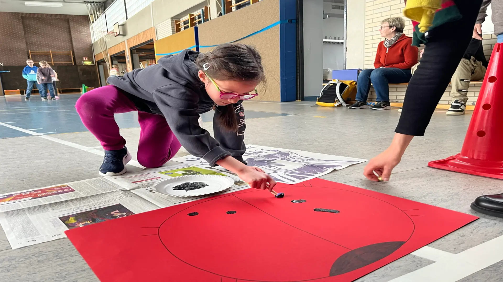 Mehrere Schüler:innen sitzen auf Matten in einer Sporthalle und spielen Torball 