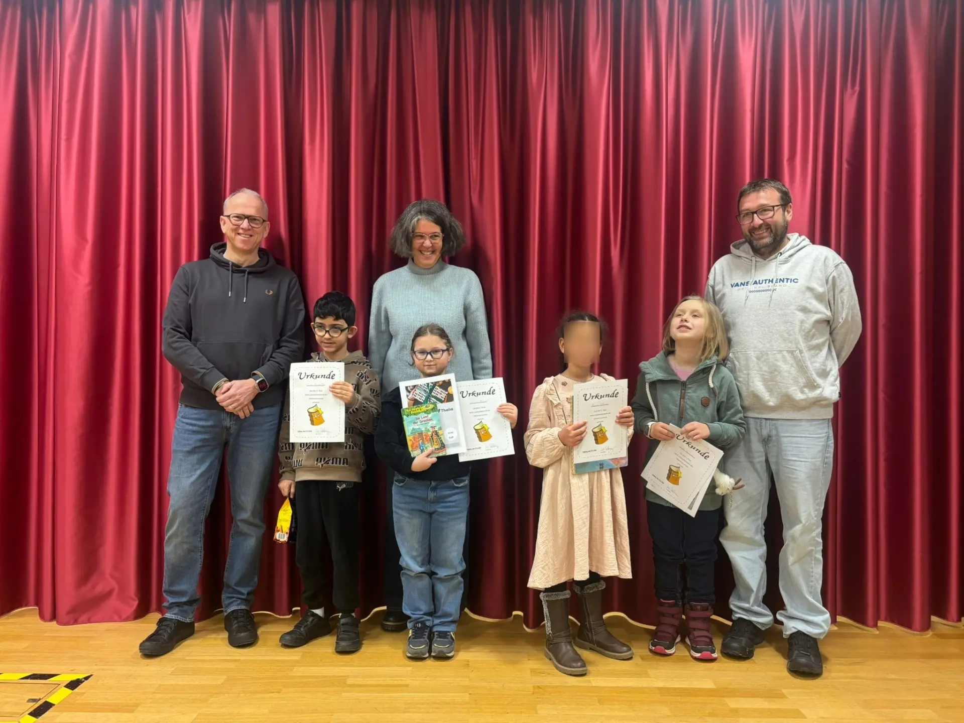 Mehrere Schülerinnen und Schüler stehen auf der Bühne und führen ein Theaterstück auf. 