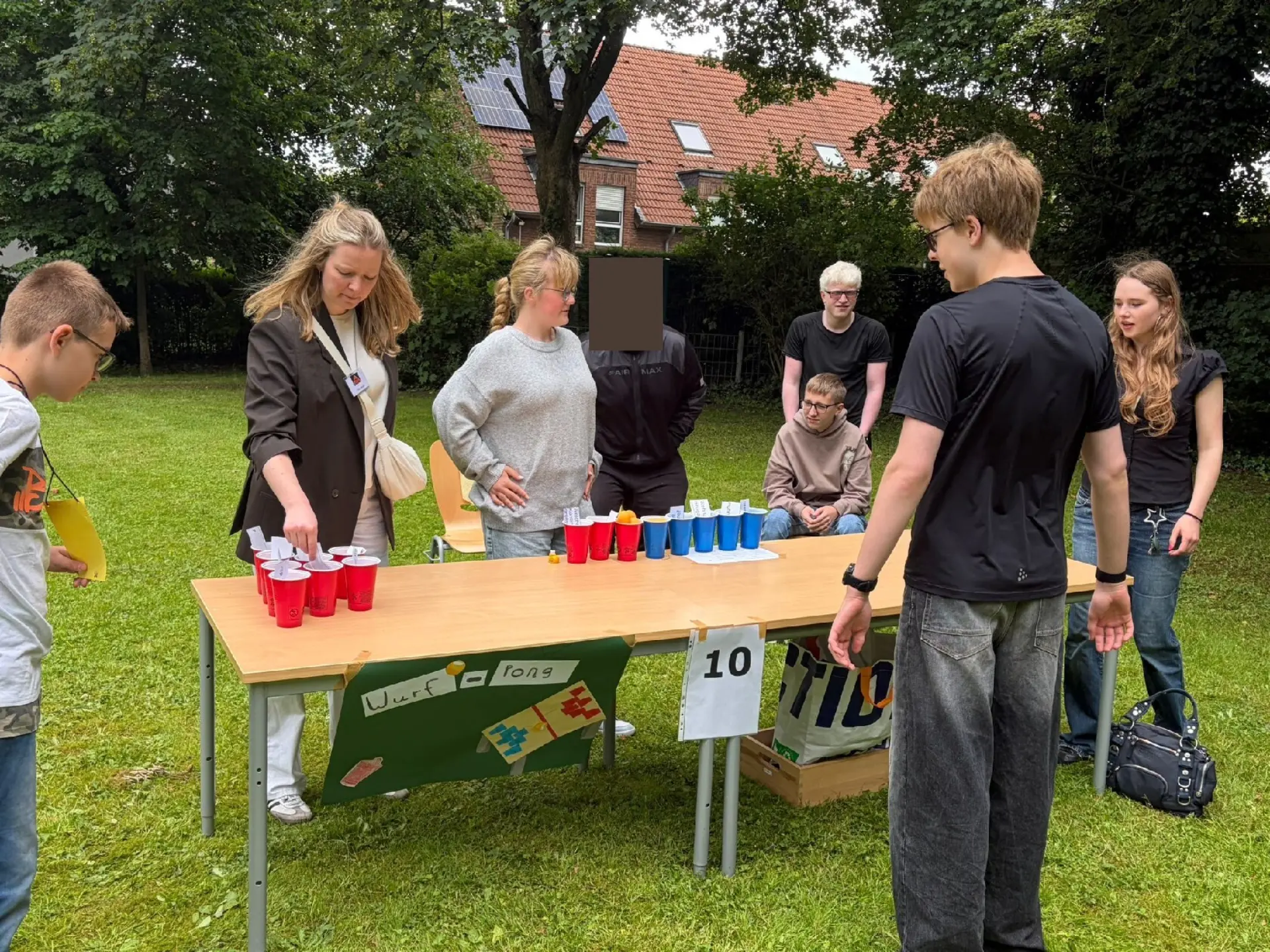 Mehrere Schüler:innen stehen gemeinsam an einem Tisch, auf dem mehrere Becher zu sehen sind