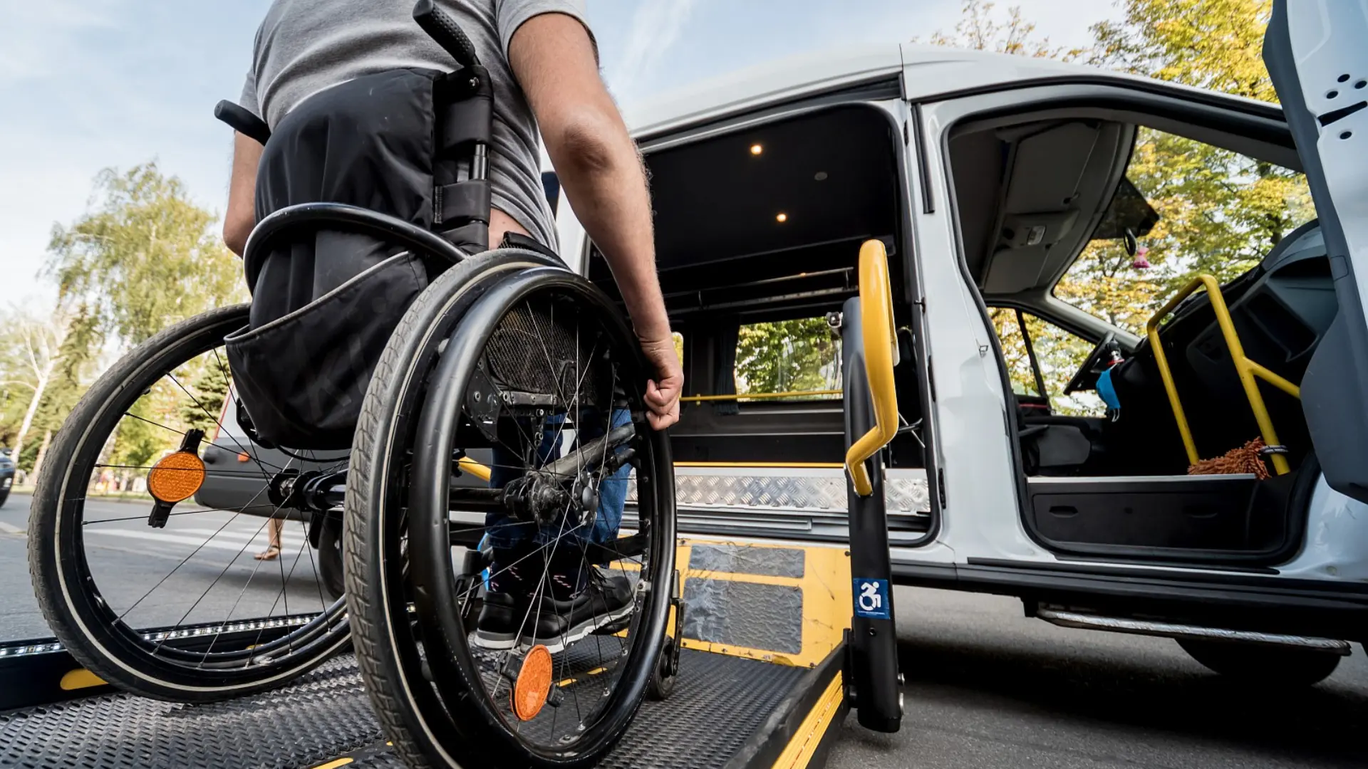 Rollstuhlfahrer fährt über eine Rampe in einen für Rollstühle ausgebauten Wagen.