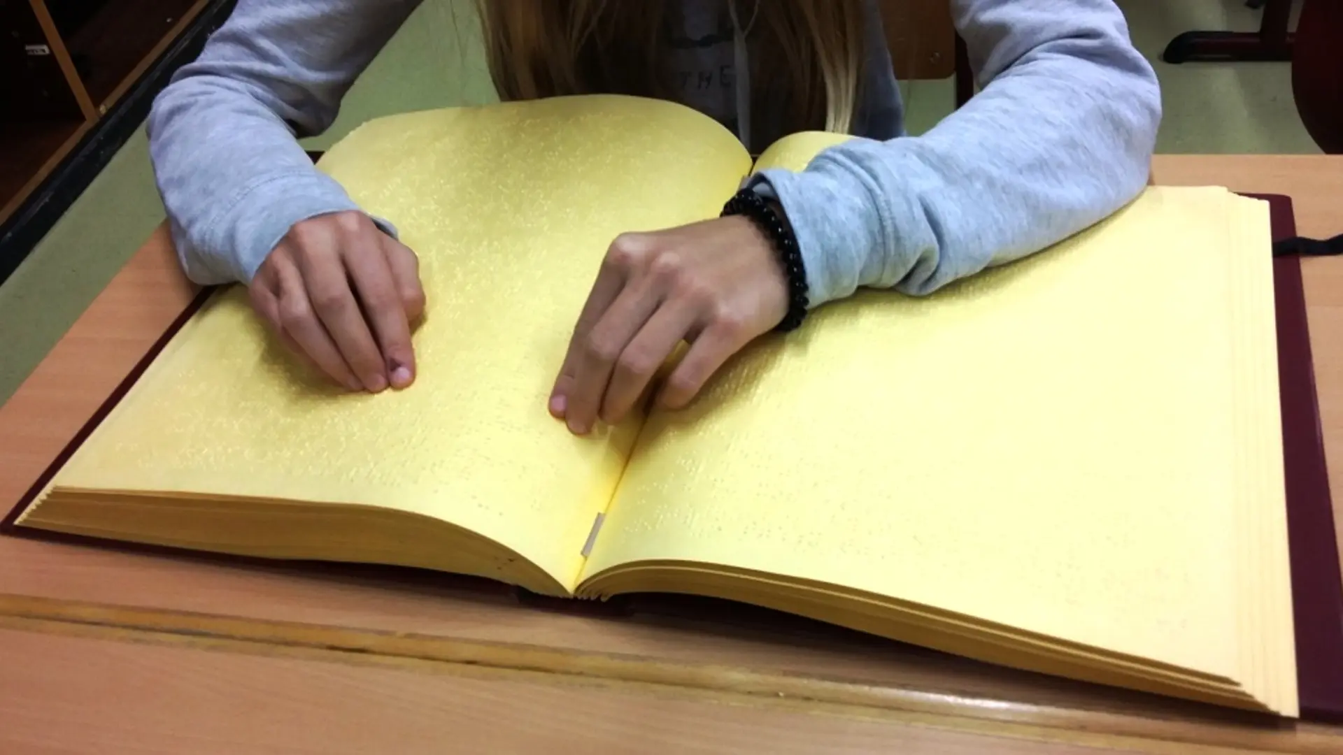Hände tasten über ein großes Buch in Punktschrift