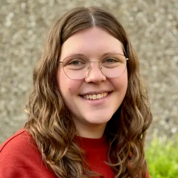 weibliche Lehrkraft mit braunen Haaren und einer Brille 