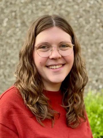 weibliche Lehrkraft mit braunen Haaren und einer Brille 